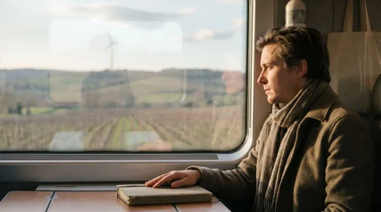 Voyageur contemplant un paysage ferroviaire français depuis une fenêtre de train