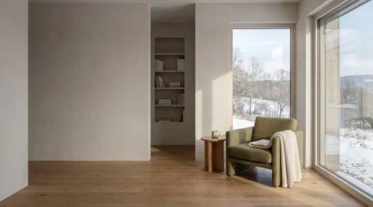 Intérieur lumineux d'une maison passive avec grande baie vitrée orientée sud, atmosphère sereine et confortable